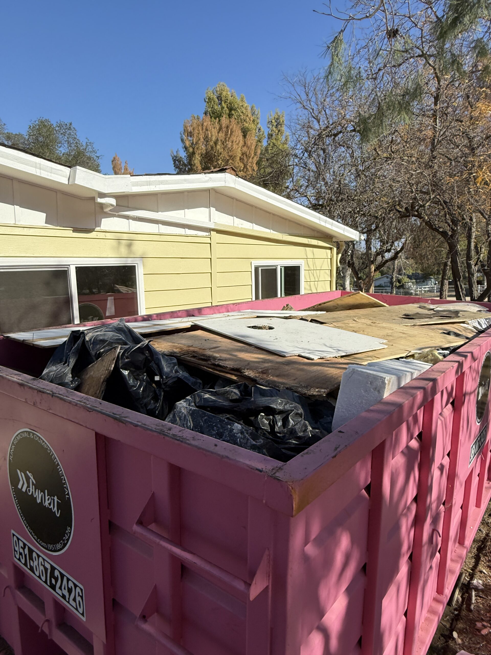 Pink dumpster rental filled with construction debris in Beaumont CA