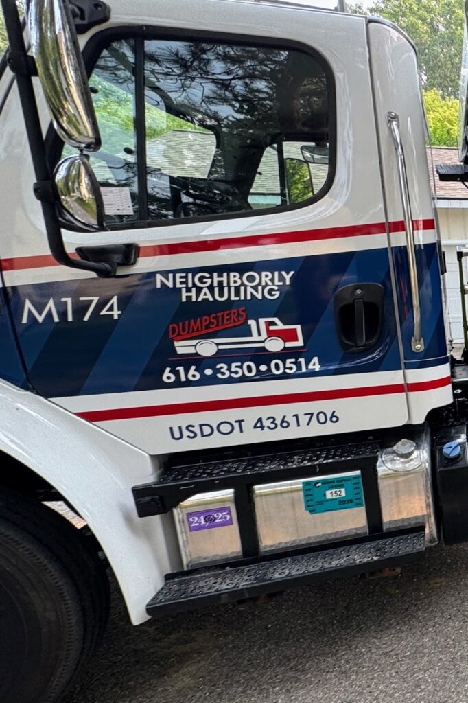 Neighborly Hauling licensed and insured dumpster truck with driver in Grand Rapids driveway