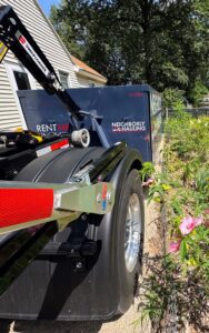 Neighborly Hauling 21 yard dumpster being placed in a Kent County driveway with Rolliskate protection.