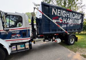 Neighborly Hauling truck loading 17 yard dumpster with hook lift