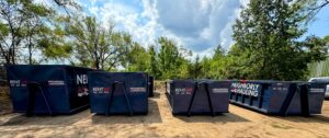 Photograph of a Neighborly Hauling 17-yard dumpster being delivered into a residential Grand Rapids driveway. The bin is set on HDPE Rolliskate pads to prevent surface damage. This container holds ~5–6 pickup truck loads and is ideal for multi-room renovations, roofing tear-offs, and siding projects.