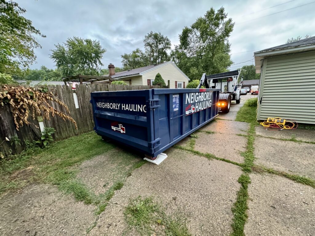 Neighborly Hauling 17-yard dumpster rental in Grand Rapids driveway with Rolliskate pads during delivery