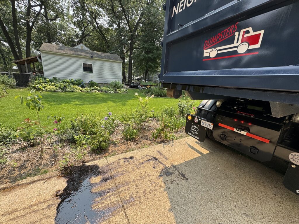 Oil leaking onto a driveway after oil was improperly dumped into a Neighborly Hauling dumpster.