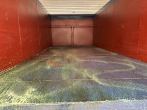 Dumpster interior being cleaned with green degreaser after oil was improperly disposed inside.