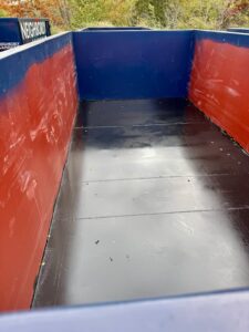 Clean, freshly painted dumpster interior with smooth black floor and red-and-blue walls.