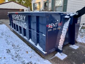 Neighborly Hauling dumpster placed on protective pads in a snowy residential driveway during winter.